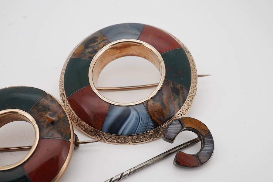 Two Scottish hardstone brooches and a stick pin, late 19th century, the brooches of annular design, the stick pin of horseshoe design, each inlaid with panels of jasper and bloodstone, largest brooch 4cm diameter, combin